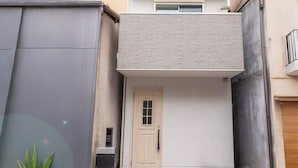 Un edificio moderno de dos pisos con techo plano, puerta principal y un pequeño vestíbulo con escalones.