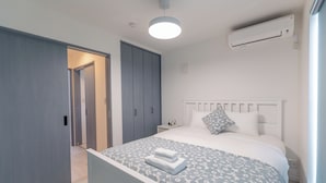 Un dormitorio con cama, armario, mesita de noche y aire acondicionado.