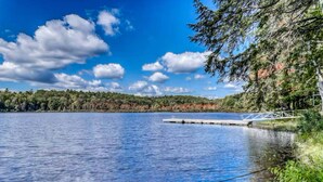 Un lac paisible, avec une jetée en bois et un pont en métal.