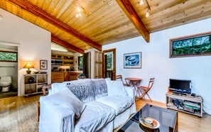 Relax in this serene living room with a sofa, table, and TV, surrounded by a forest view.