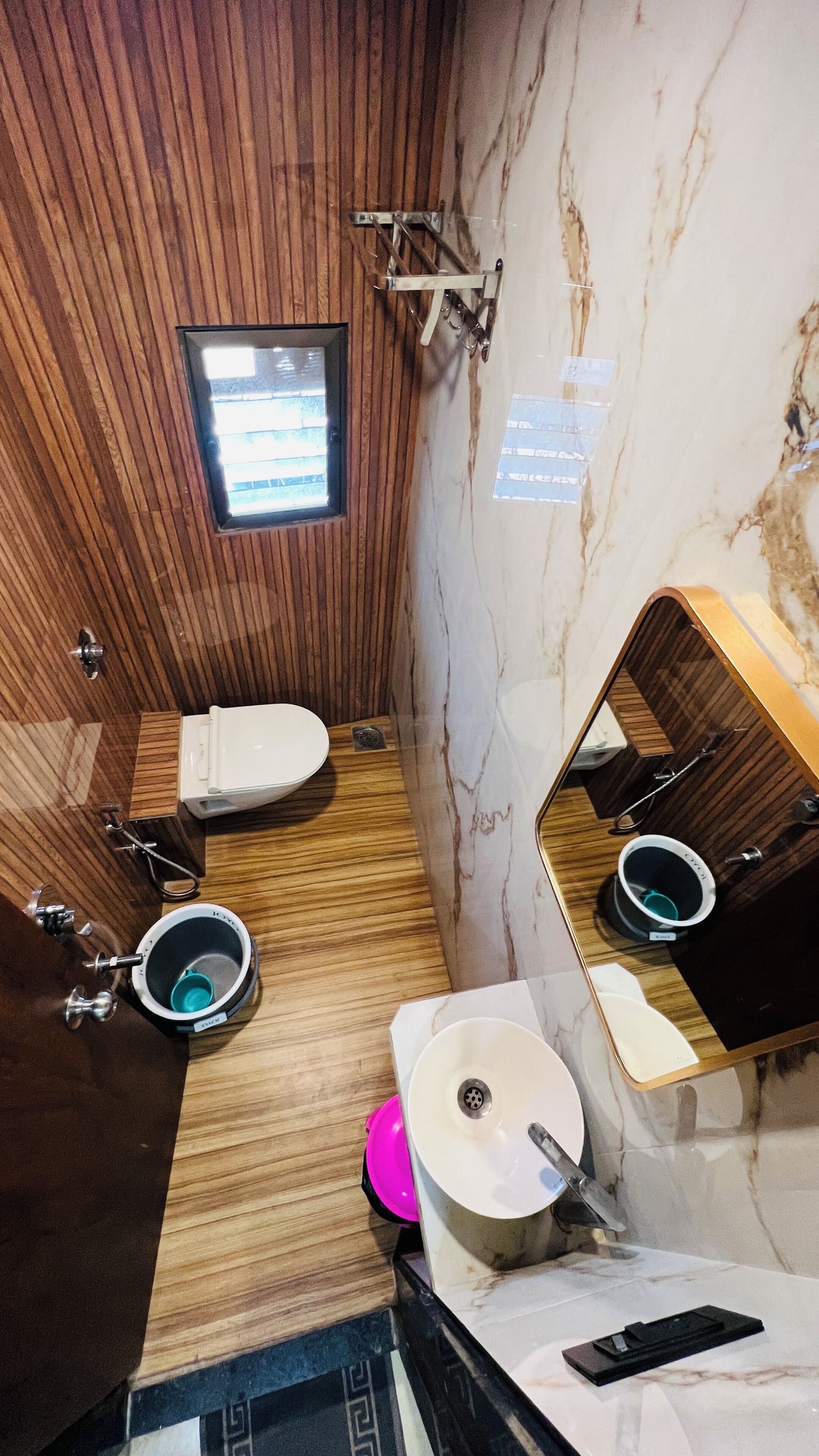 A bathroom with a wooden panel wall, a marble sink, a toilet, and a mirror.