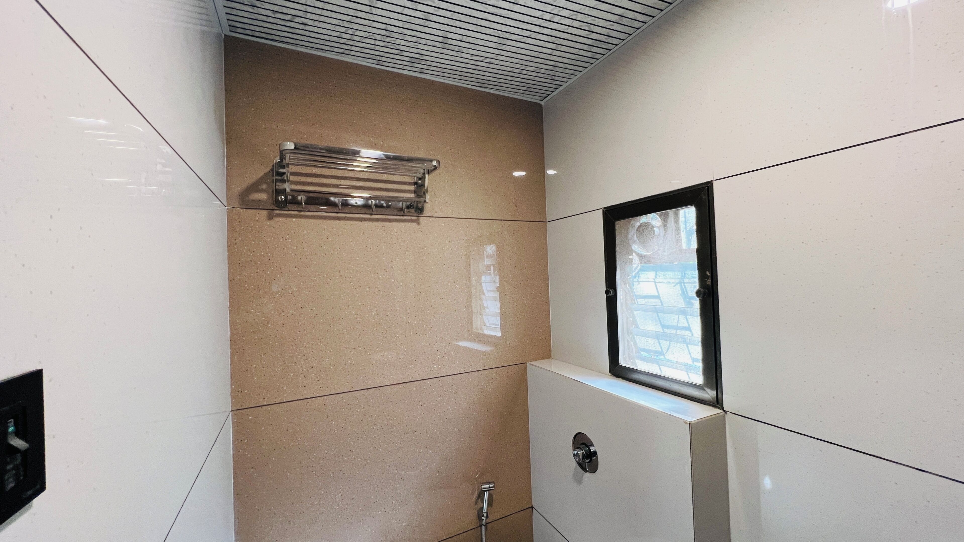 Une salle de bain avec une douche, une fenêtre et un porte-serviettes.