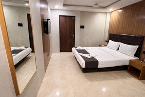 Una habitación de hotel moderna con una cama grande, cabecera de madera, televisor de pantalla plana en la pared y mesita de noche de madera.