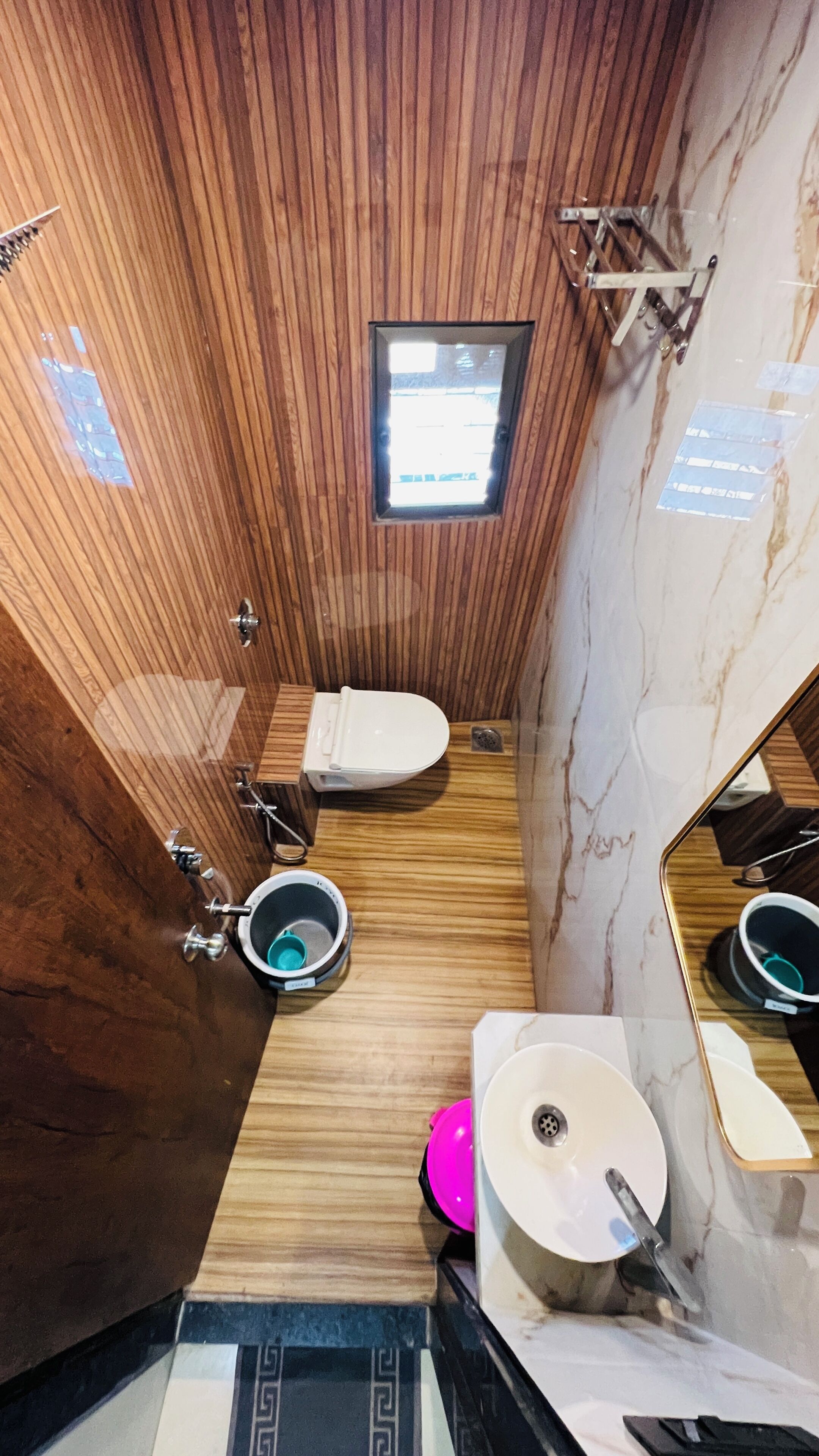 Une petite salle de bain avec un plafond en bois, une petite lucarne, des toilettes, un lavabo et un miroir.