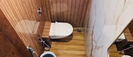 Een kleine badkamer met houten plafond, klein dakraam, toilet, wastafel en spiegel.