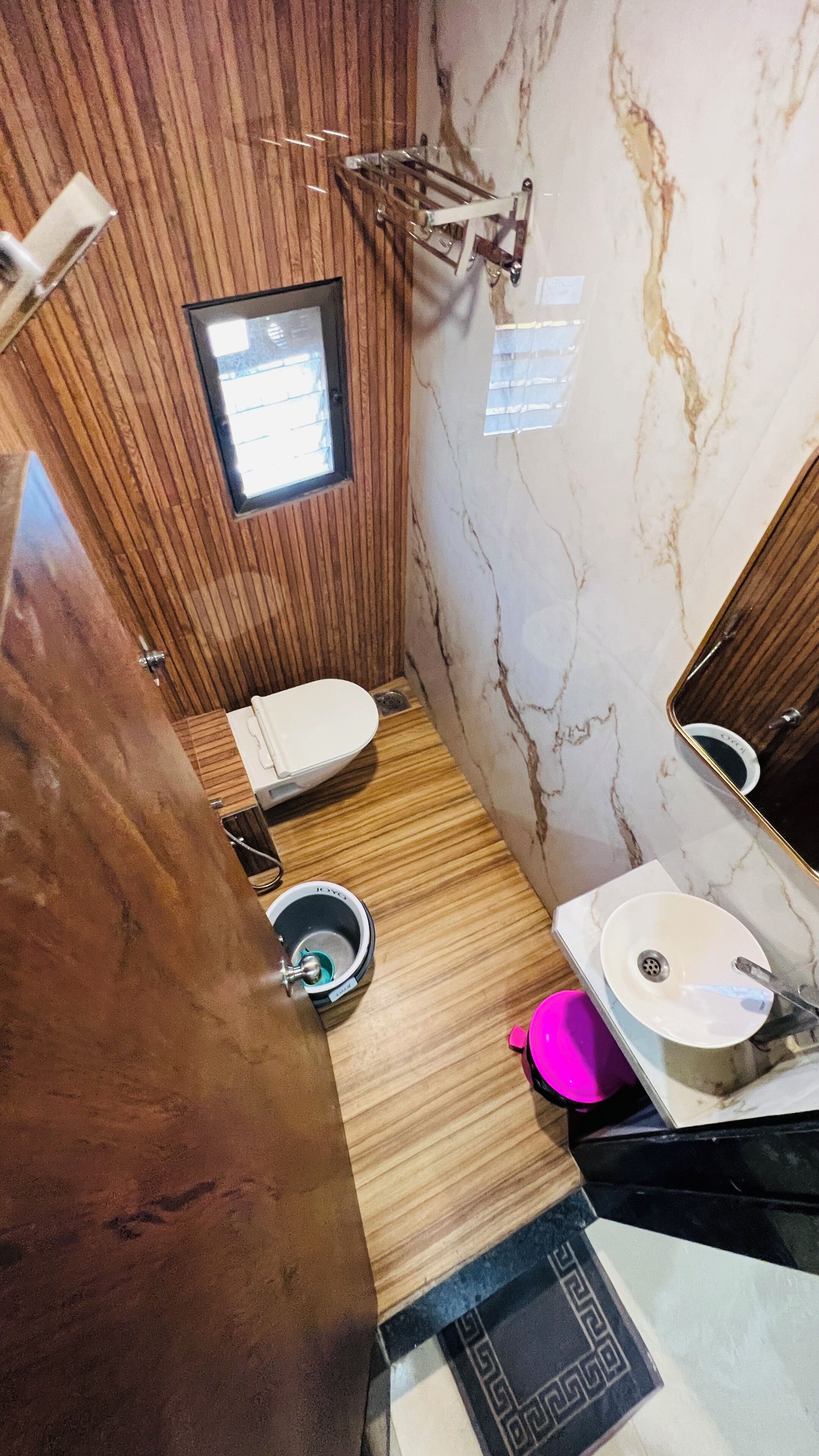 A compact bathroom with a wooden vanity, a white sink, and a small window.