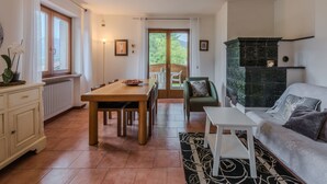 Een ruime woonkamer met een houten eettafel, een bank en een open haard.