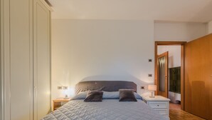 Een slaapkamer met een groot bed, twee nachtkastjes, een spiegel en een kledingkast.