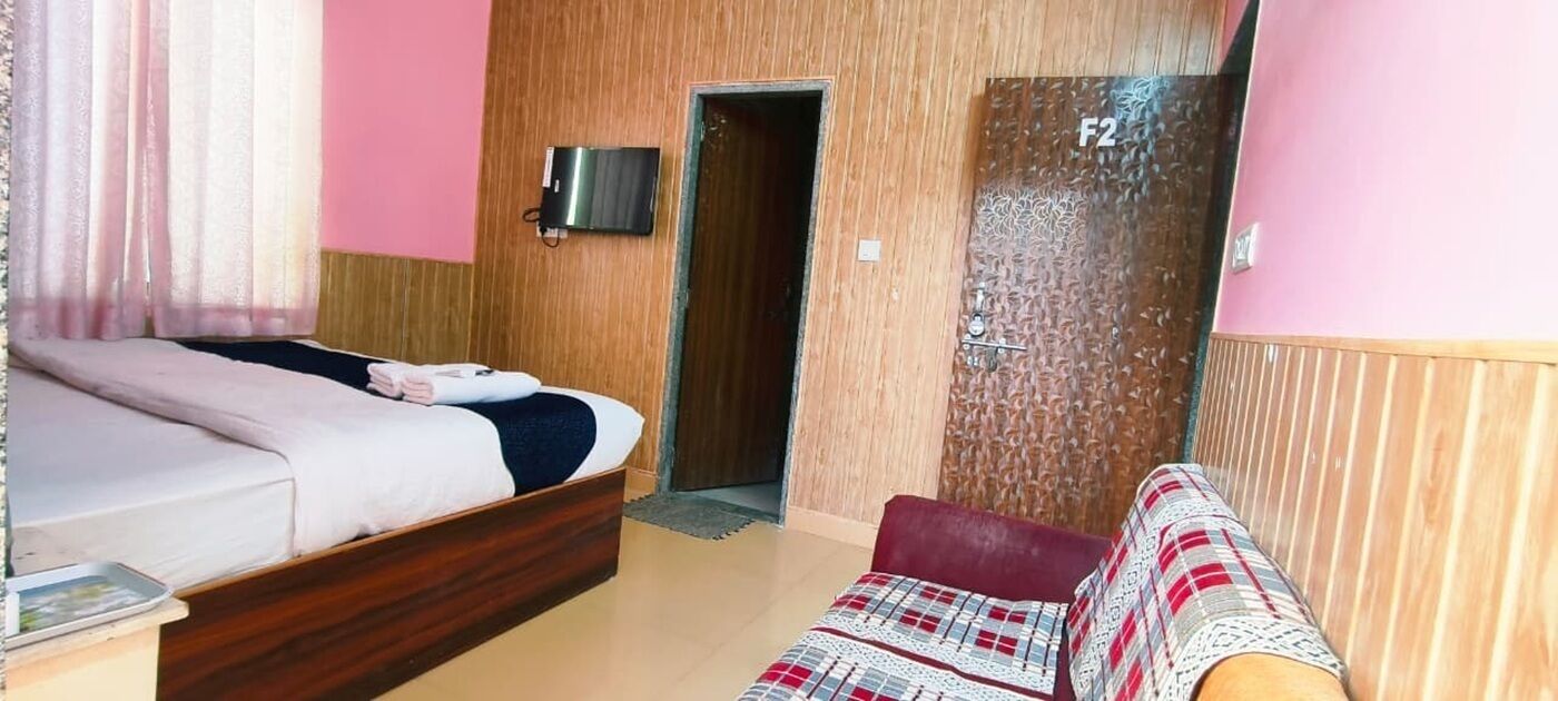 A room with a bed, a sofa, a wall-mounted TV, and a door marked 'F2'.