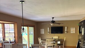 A spacious kitchen with a large island, wooden cabinets, and a dishwasher. There is a dining area with a table and chairs, and a ceiling fan above.