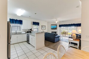 Une cuisine moderne avec des meubles blancs, un îlot central et un coin repas comprenant une table et des chaises en bois.