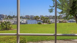 A marina with boats docked, a grassy area, and residential buildings in the background.