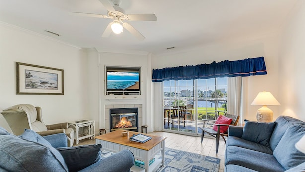 A living room with a fireplace, a television, and a view of the outdoors.