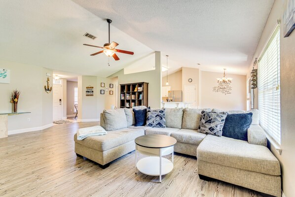 Relax in this inviting living room with a large L-shaped sofa, round coffee table, and bookshelf.