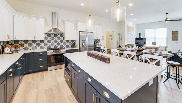 Una cocina moderna con una isla grande, armarios blancos y un salpicadero con diseño.