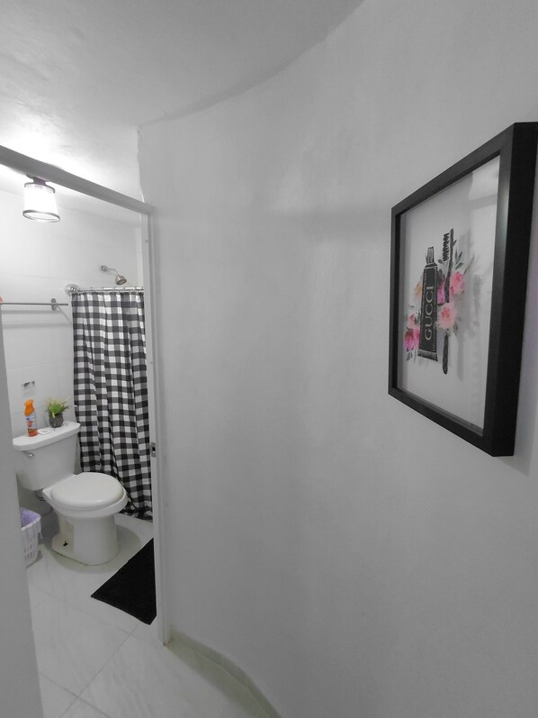 Un baño con inodoro, cortina de ducha y un cuadro en la pared.