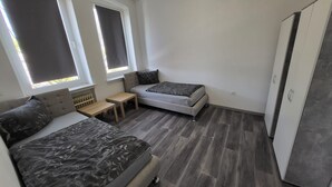 Une chambre à coucher de taille modeste, comprenant deux lits, une petite table et une armoire.