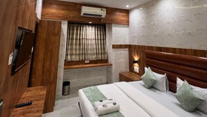 Ein modernes Hotelzimmer mit einem großen Bett, einem Holz-Kopfteil und einem Deckenventilator.