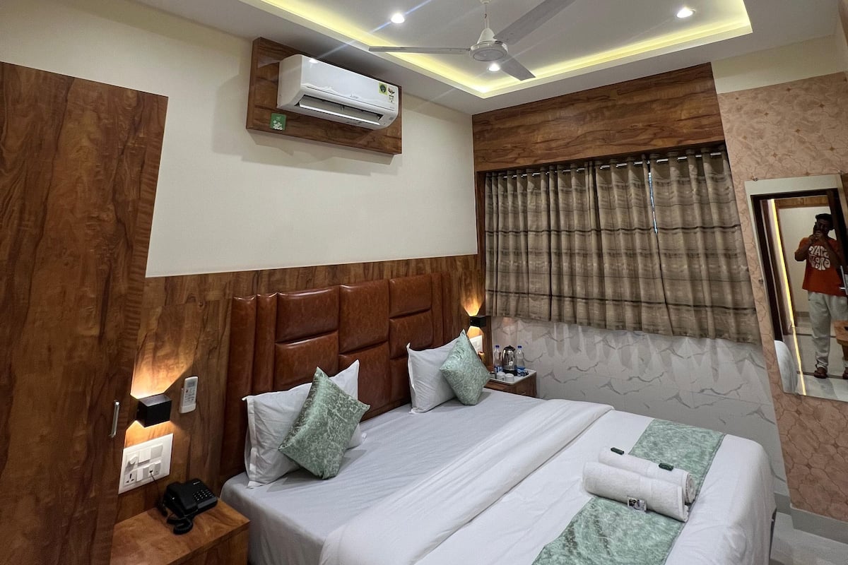 Una habitación de hotel moderna con una cama grande, cabecero de madera e iluminación empotrada en el techo.