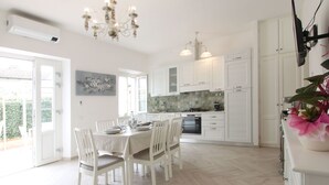 A spacious kitchen with white cabinetry, a dining table set for four, and a chandelier. - Villa Gabriele by Interhome (Forte dei Marmi)