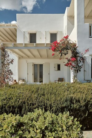 A white building with a balcony, a door, and a small table with chairs.