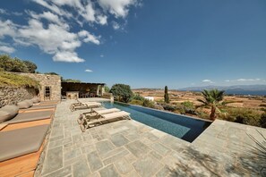 Ein Poolbereich mit Liegestühlen und einer Steinsäule, mit Blick auf eine reizvolle Landschaft.