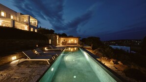 A modern house with a swimming pool, lounge chairs, and a stone building in the background. - Villa Inke - Secluded Luxury (Kostos)