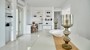 A modern, minimalist interior with white walls, built-in shelving, and a central dining area with a table and chairs. - Villa Inke - Secluded Luxury (Kostos)