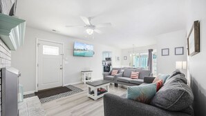 A modern living room with a grey sofa, a coffee table, and a TV mounted on the wall.