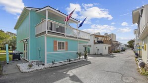 A two-story building with a balcony, a flag, and a small garden area.