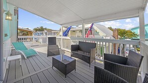 A covered outdoor deck with wicker furniture and a view of the surrounding area.