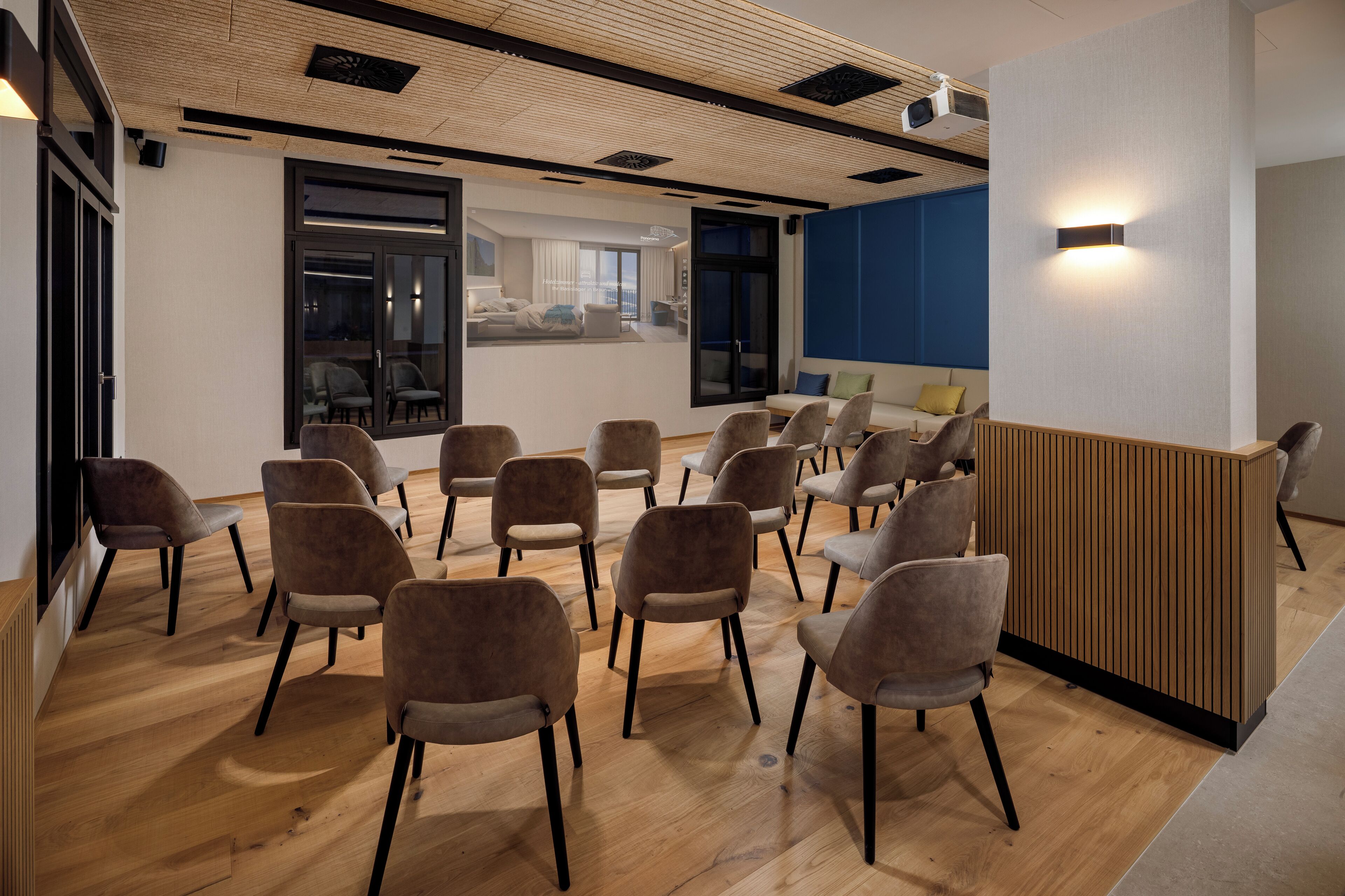 Ein Konferenzraum mit Holzböden, grau gepolsterten Stühlen und einem Holzbüro.