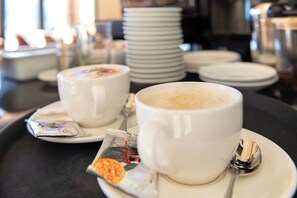 Two white cups of coffee on a tray with a spoon and a packet of creamer. - Panoramahotel Braunwald (Glarus Sued)