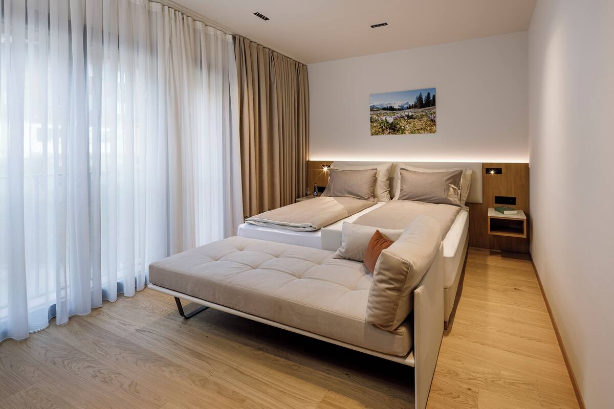 Ein modernes Schlafzimmer mit einem großen Bett, einem Nachttisch und einer Wandleuchte.