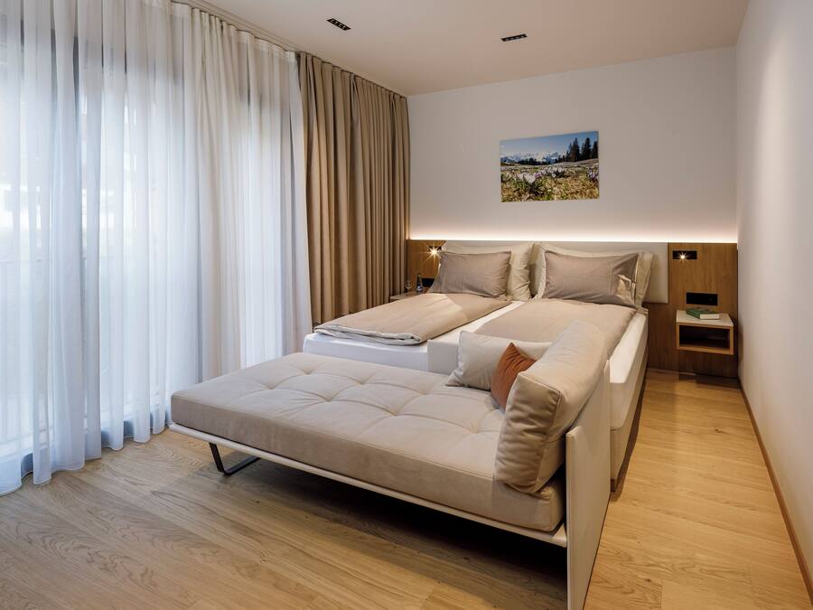 Ein modernes Schlafzimmer mit einem großen Bett, einem Nachttisch und einer Wandleuchte.