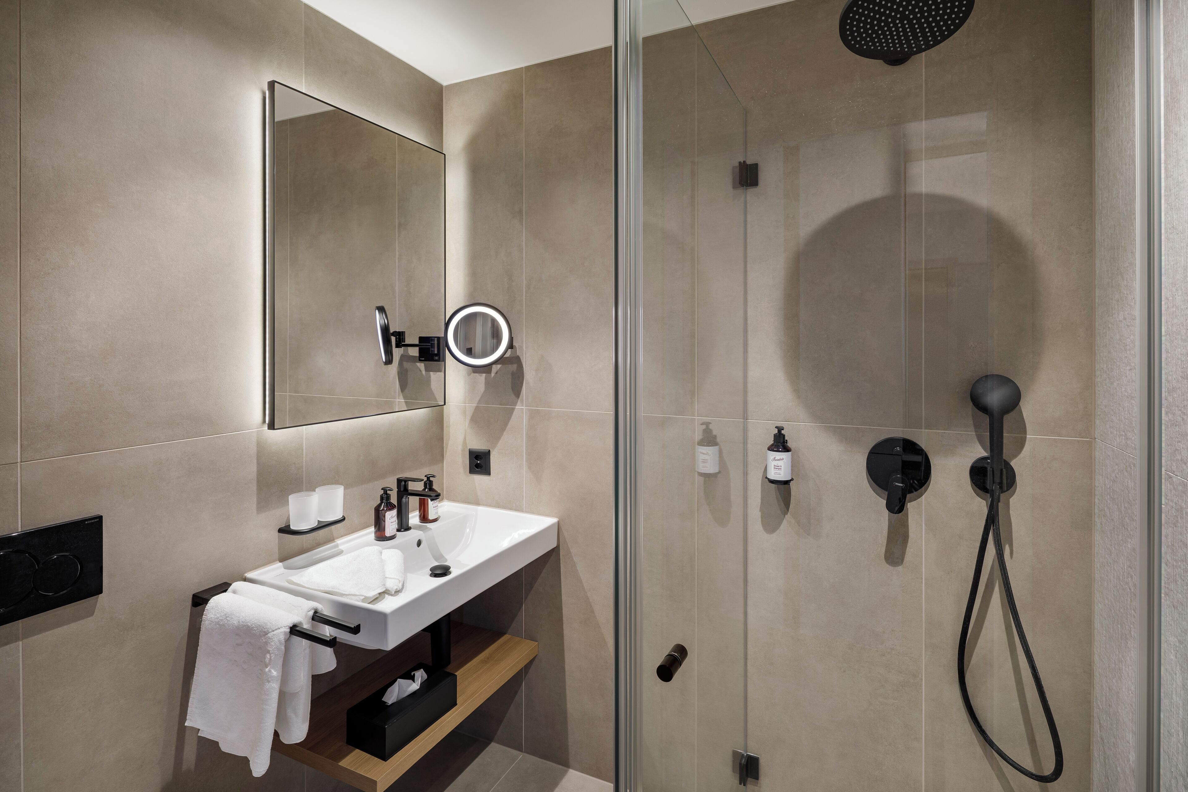 Un baño moderno con cabina de ducha de vidrio, un lavabo con espejo y un perchero para toallas.