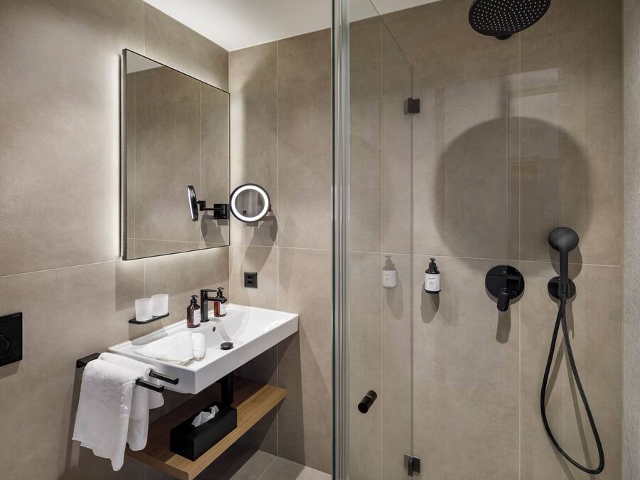 Un baño moderno con cabina de ducha de vidrio, un lavabo con espejo y un perchero para toallas.