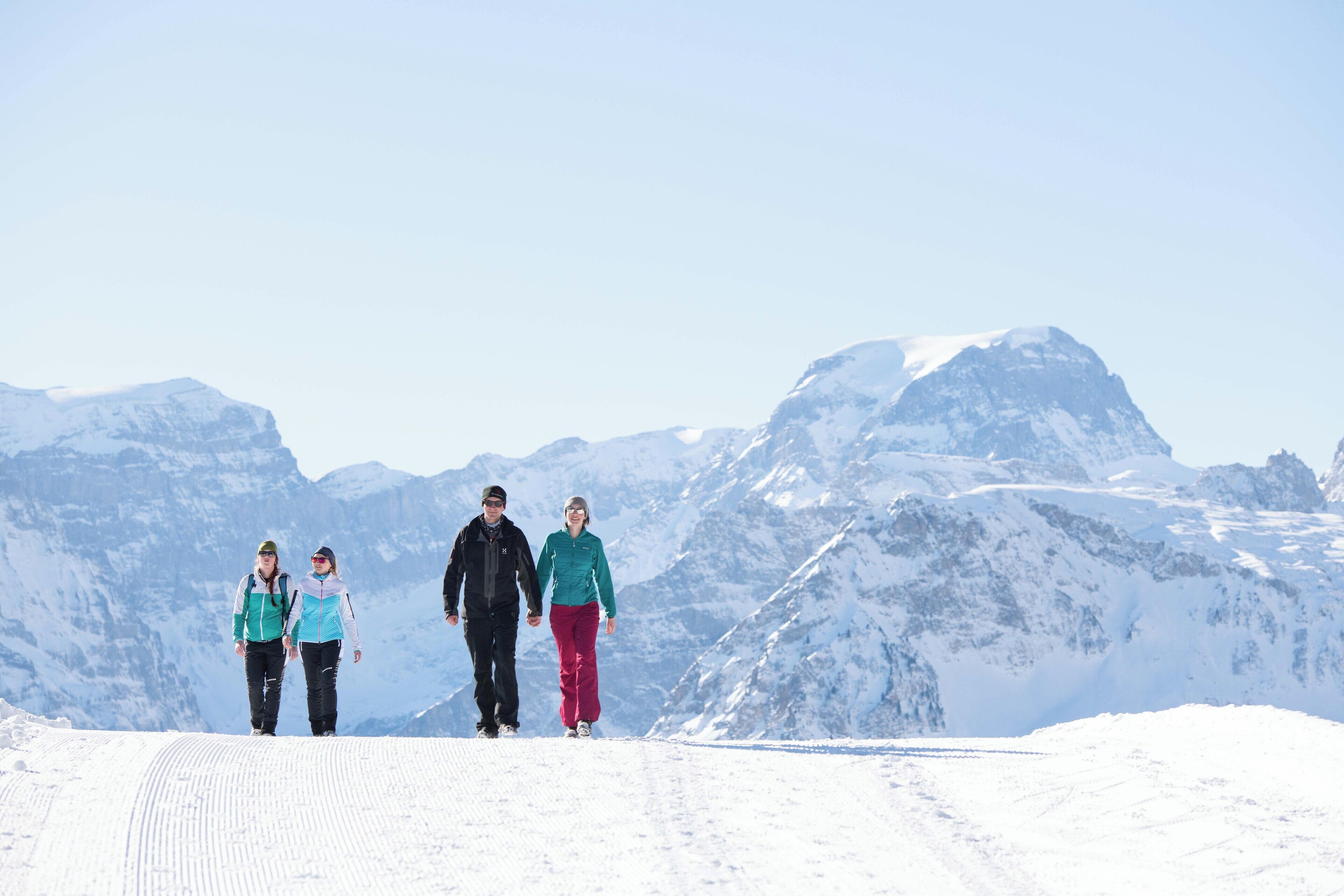 Un sentier de montagne enneigé sur lequel marchent trois personnes.