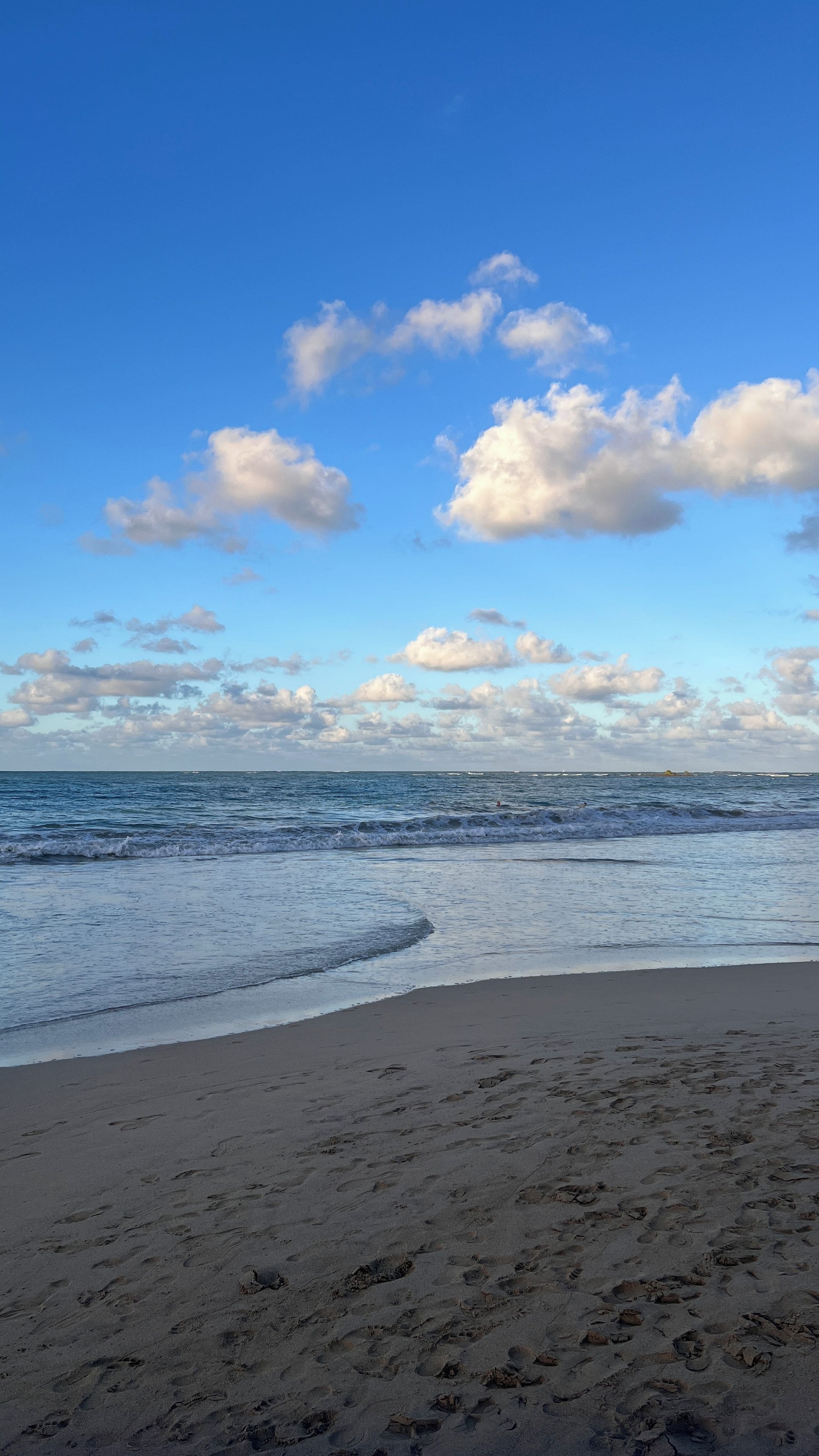 A beach with footprints in the sand and a clear sky.