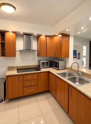 A modern kitchen with wooden cabinets, stainless steel appliances, and a granite countertop.