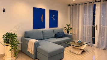 A modern living room with a sectional sofa, a glass coffee table, and two wall-mounted paintings.