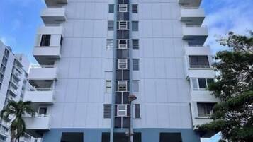 A high-rise building with a central vertical corridor, multiple balconies, and a flat roof.