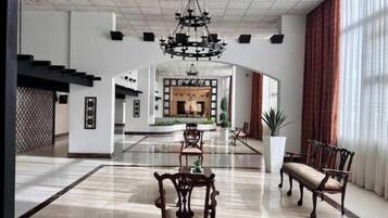 A spacious lobby with a high ceiling, a chandelier, and a seating area with wooden chairs and a bench.