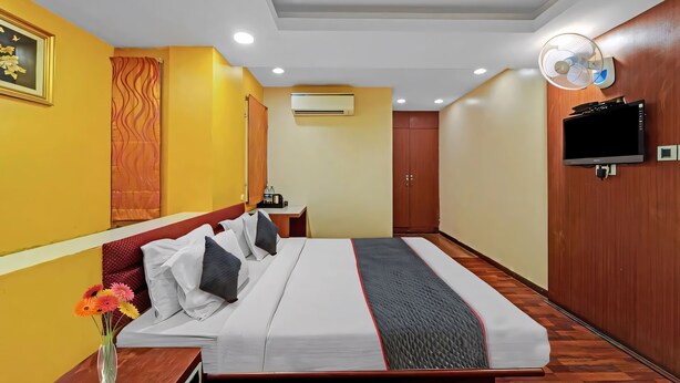 Een hotelkamer met een bed, nachtkastje en een aan de muur bevestigde televisie.