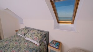 Ein Schlafzimmer mit einem Bett, einem Fenster und einem kleinen Tisch mit Büchern.