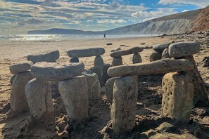 Una platja amb estructures de pedra i una persona caminant a la distància.