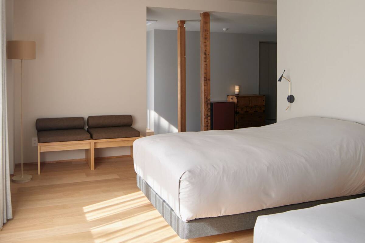 Un dormitorio moderno con una cama grande, un banco con cojines y suelo de madera.