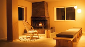 Una habitación acogedora con chimenea, una mecedora y un banco.