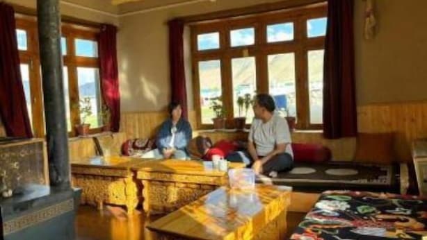 Una habitación tradicional con sofá, una mesa de madera y un ventanal con cortinas.