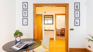 Een moderne kamer met een ronde tafel, stoelen, een potplant en afbeeldingen in lijsten aan de muur.